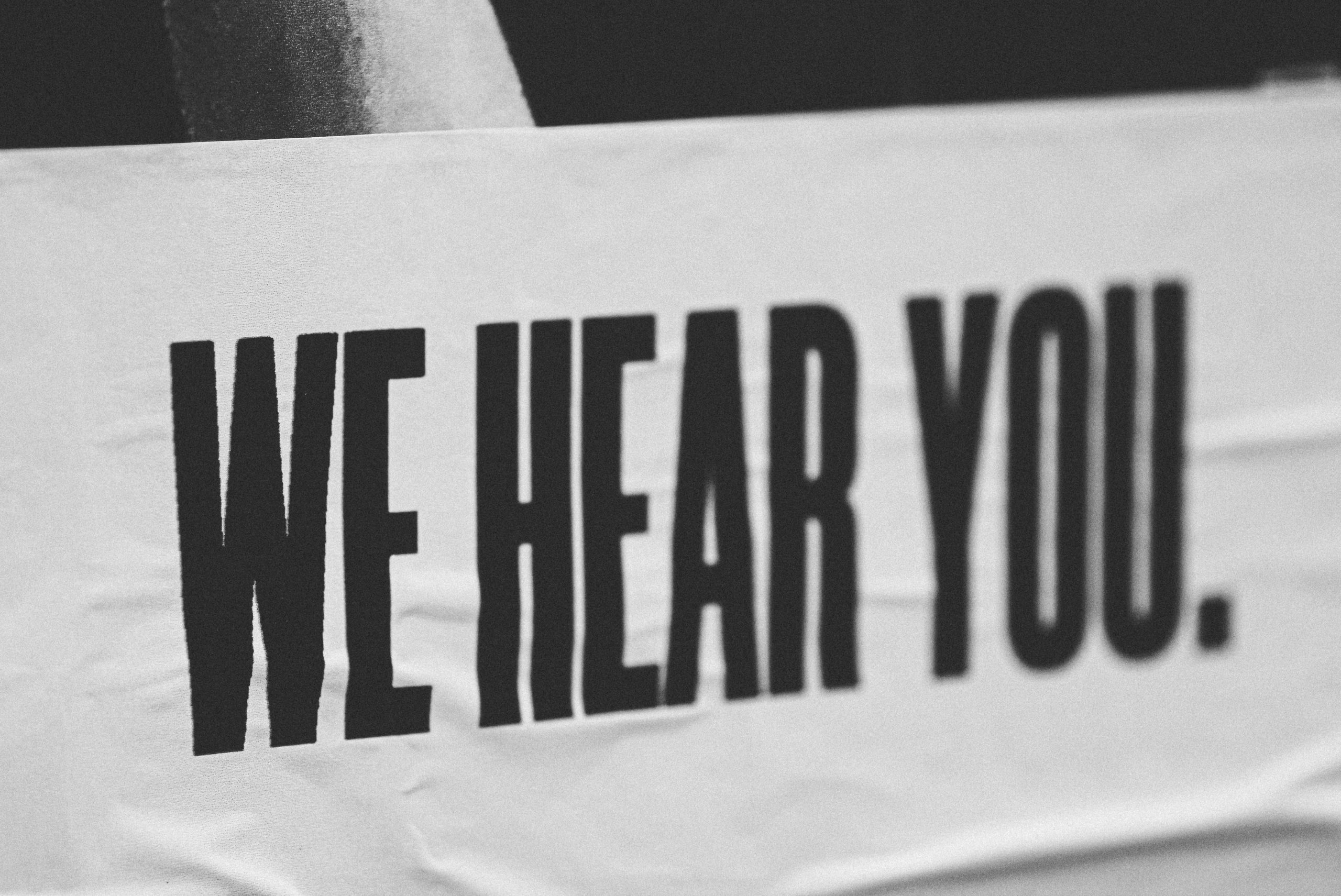 Una pancarta blanca con el texto "Te escuchamos" en letras negras en negrita